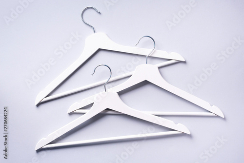 White clothes hangers on grey background with copy space. Flat lay. Top view. Minimalism style. Creative layout. Fashion, store sale, shopping concept. Banner for feminine blog