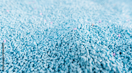 Close up large pile of blue plastic granules in temporary storage of production line at recycle factory, masterbatch dye polymer plastics resin pellet background,  injection molding process lab