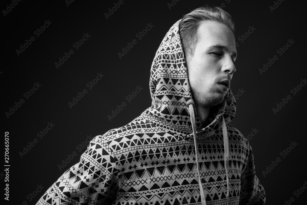 Studio shot of young handsome man against gray background in bla