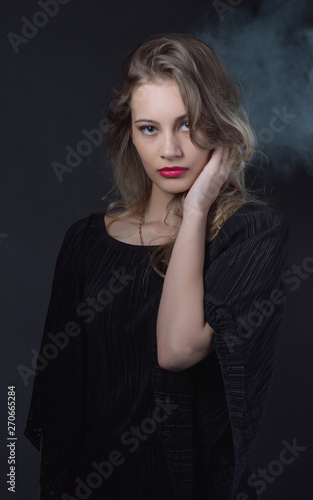 Beautiful ,young blonde with bright red lips and expressive eyes in a black jumpsuit. Beauty portrait of a girl. Emotional and bright appearance. Fashion portrait of a woman.