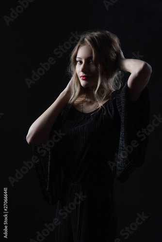Beautiful ,young blonde with bright red lips and expressive eyes in a black jumpsuit. Beauty portrait of a girl. Emotional and bright appearance. Fashion portrait of a woman.