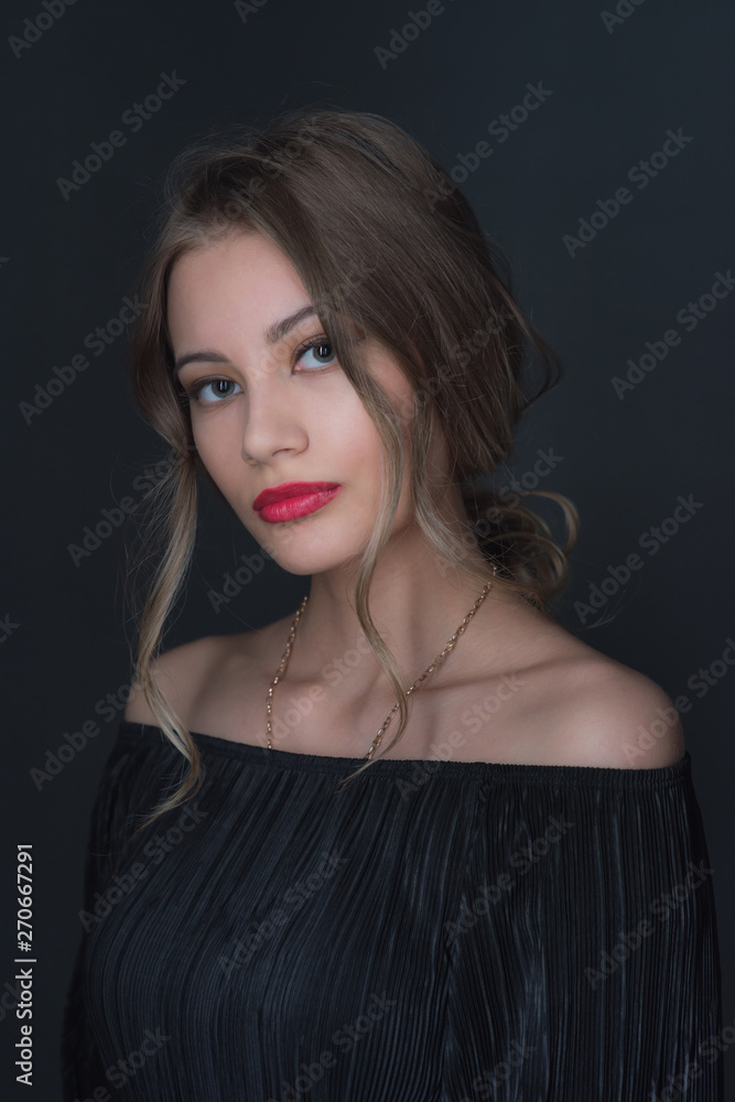 Fototapeta premium Beautiful ,young blonde with bright red lips and expressive eyes in a black jumpsuit. Beauty portrait of a girl. Emotional and bright appearance. Fashion portrait of a woman.