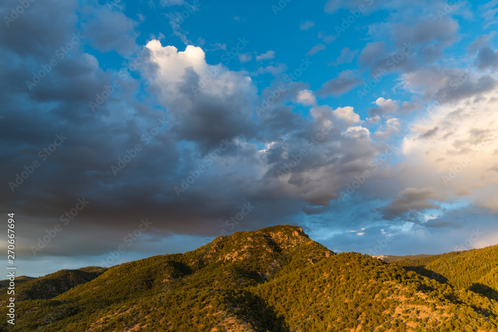 Fototapeta premium Światło zachodu słońca podkreśla las sosnowy i jałowcowy oraz szczyt górski pod dramatycznym wieczornym niebem - góry Sangre de Cristo w pobliżu Santa Fe w Nowym Meksyku