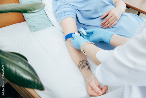 partial view of doctor using tourniquet for blood test in hospital