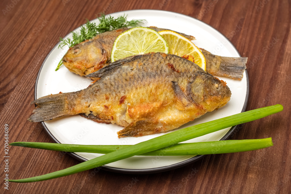 Fried carp fish on white plate. Ready meal. Wooden background Fried carp fish on white plate. Ready meal. Wooden background