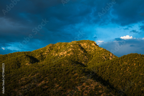 Beautiful sky and clouds over a mountain peak highlighted the setting sun - Sangre de Cristo Mountains near Santa Fe, New Mexico