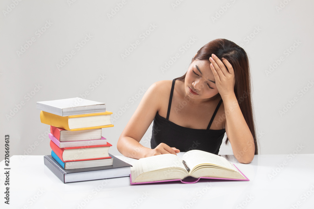 Exhausted Young Asian woman read a book with books on table. Exhausted Young Asian woman read a book with books on table.