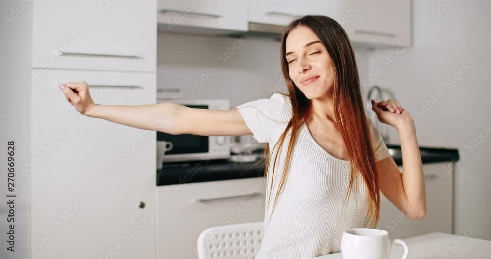 Happy pretty young woman stretching in the kitchen in the morning Happy pretty young woman stretching in the kitchen in the morning