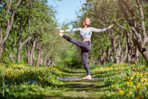 Photo of young girl standing on one leg in yoga in forest