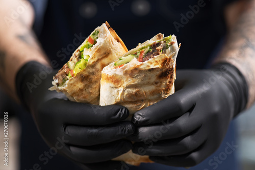 Burrito, lamb shawarma - the best street food. Close-up of men's hands chefs with shawarma. photo