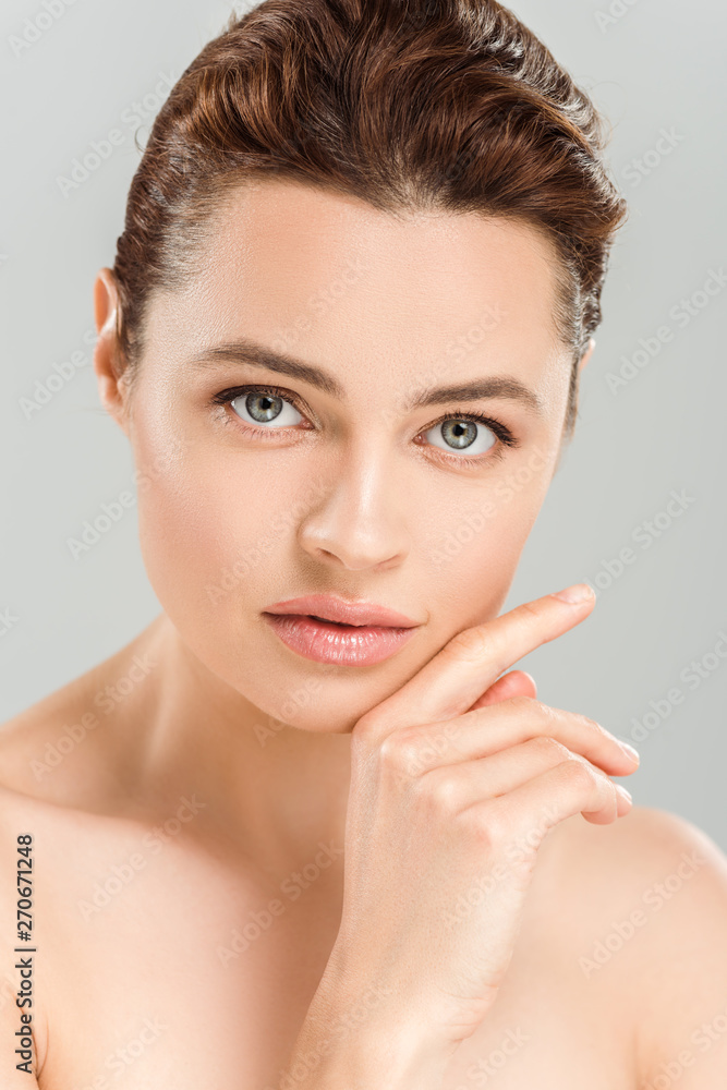 serious naked woman looking at camera and touching face isolated on grey serious naked woman looking at camera and touching face isolated on grey