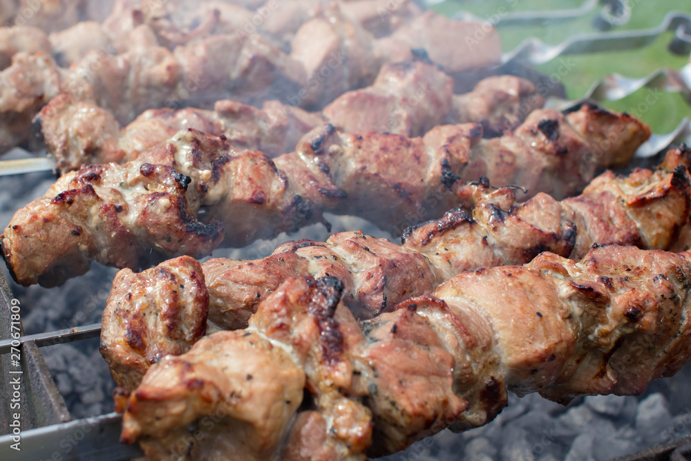 Shashlik pork on skewers close up. Meat roasted on an open fire on the grill. Selective focus.