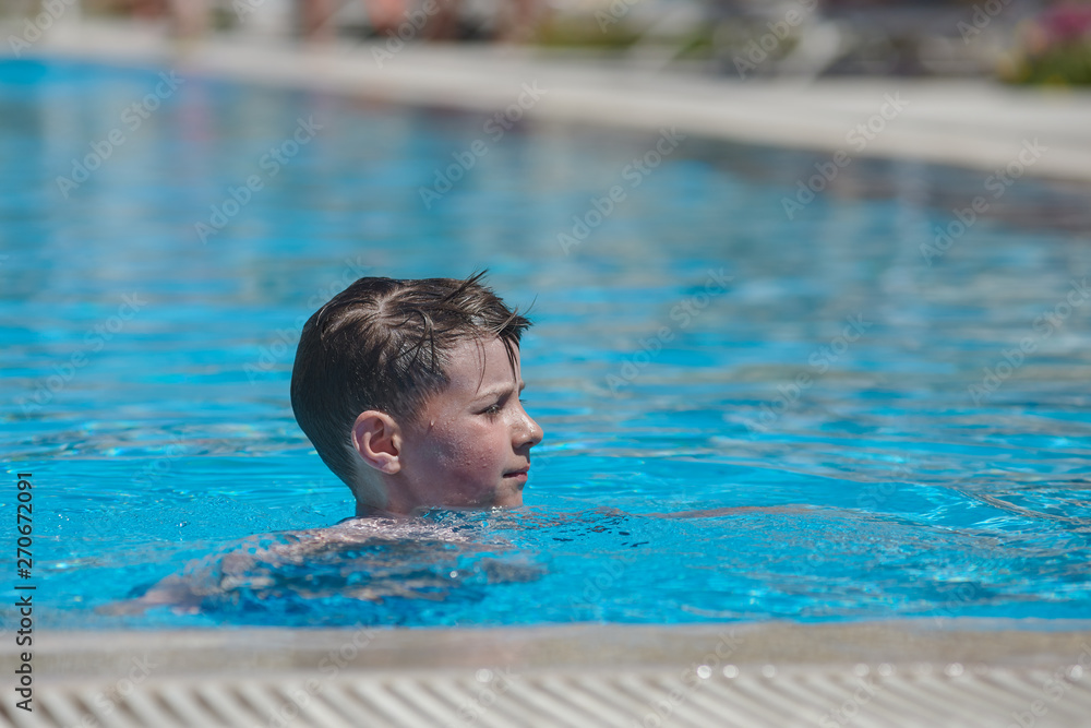 Portrait of Caucasian boy in swimming pool at resort.