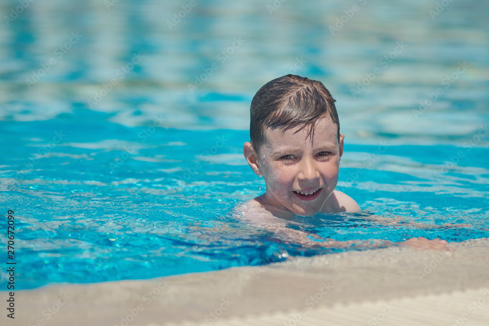Cute European boy is enjoying his summer vacations. He is having fun in the hotel’s pool.