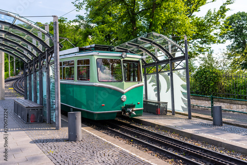 A green cog railway car standing on the tracks at the bus stop.
