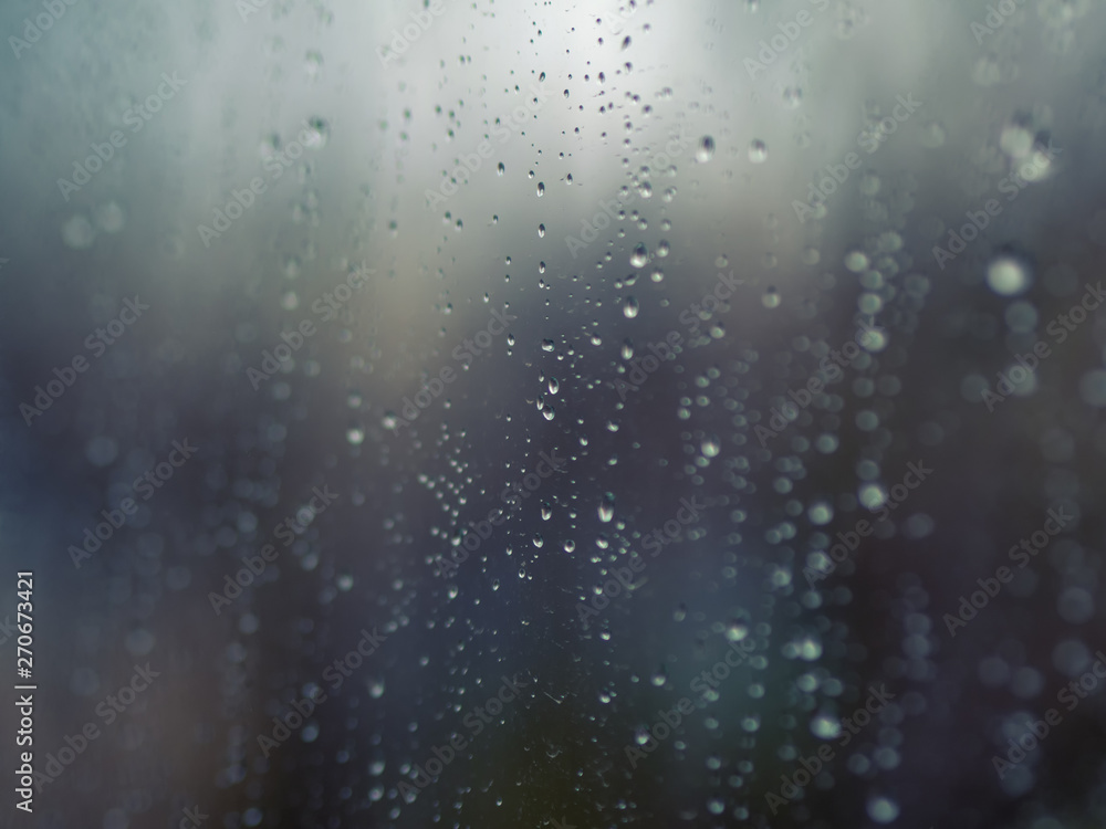 ..Raindrops on the surface of window glass with a blurred background.