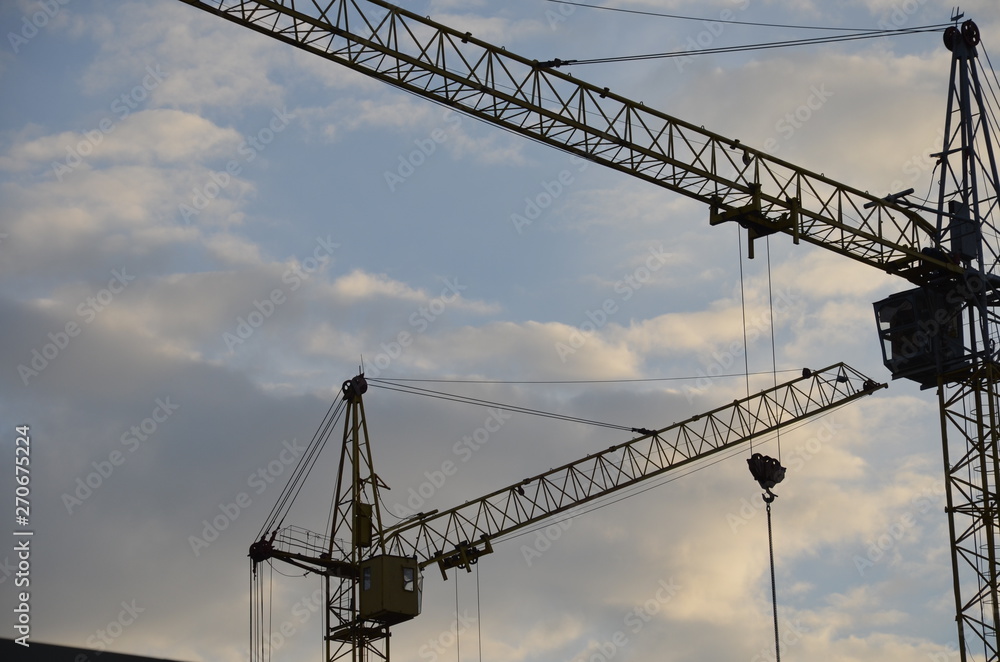 Construction crane near the building under construction. Close up of a construction crane. Self-erection crane. Construction site Construction crane near the building under construction. Close up of a construction crane. Self-erection crane. Construction site