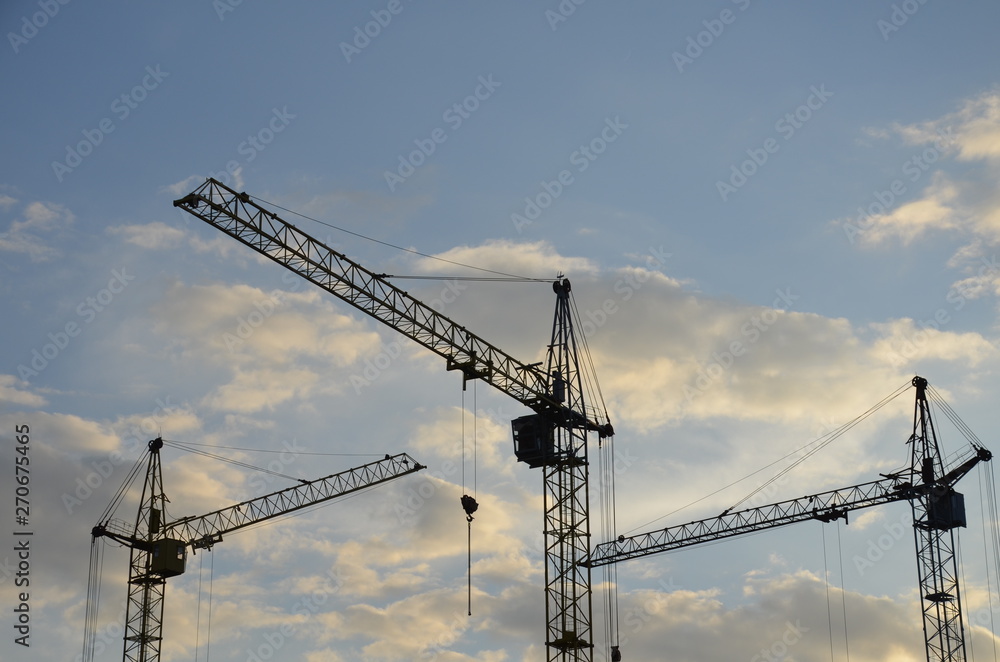Construction crane near the building under construction. Close up of a construction crane. Self-erection crane. Construction site Construction crane near the building under construction. Close up of a construction crane. Self-erection crane. Construction site