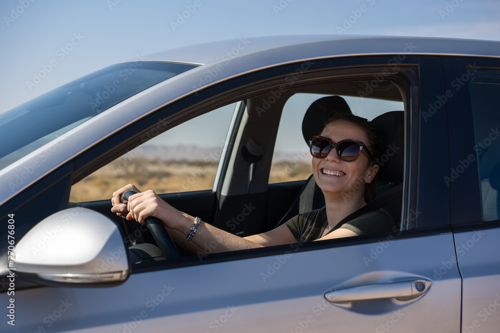 happy young woman driving a rented car in the desert of israel
