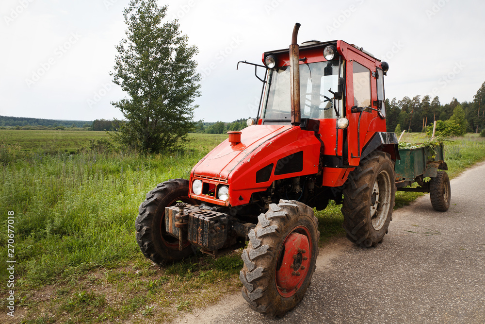 Old red rusty tractor with trailer in field Old red rusty tractor with trailer in field