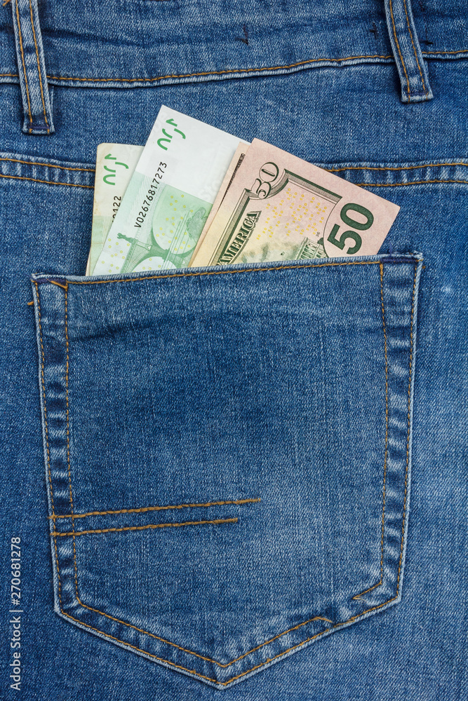 Close Up View to 100 euro and 50 dollar Banknotes Sticking Out From a Blue Jeans Pocket Close Up View to 100 euro and 50 dollar Banknotes Sticking Out From a Blue Jeans Pocket
