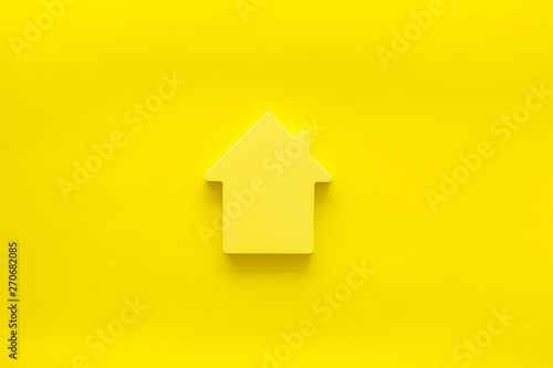 Property insurance concept with house toy on yellow background top view