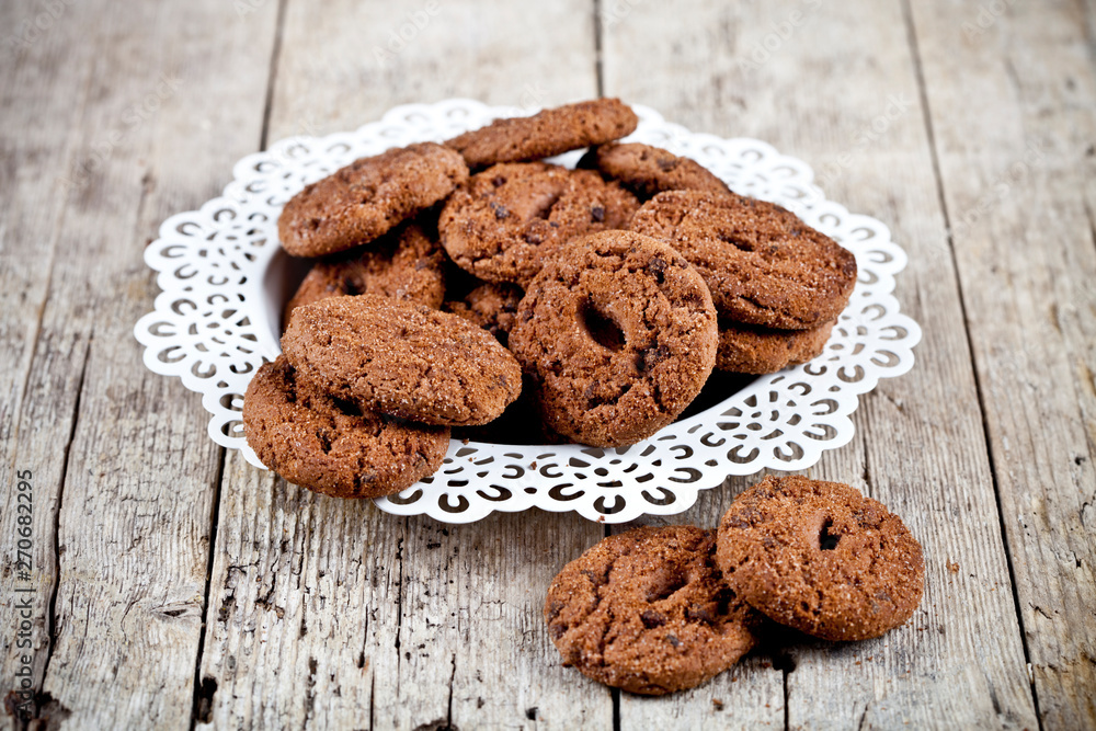 Fresh baked chocolate chip cookies heap on white plateon rustic wooden table. Fresh baked chocolate chip cookies heap on white plateon rustic wooden table.