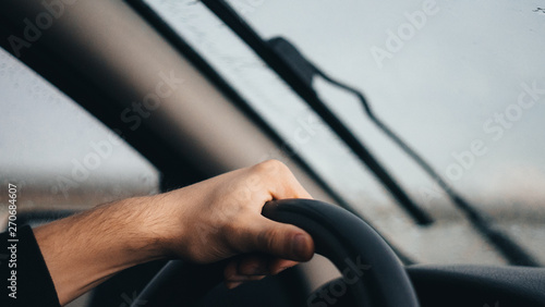 Man driving a car with one hand on the steering wheel. wet car window in rainy day. rain Drops on car window pane. Dangerous Driving. storm rainy season
