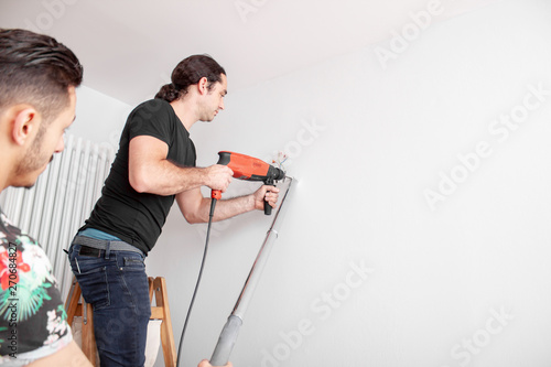 Handwerker bohrt Loch in die Wand mit einer Schlagbohrmaschine in einer Wohnung
