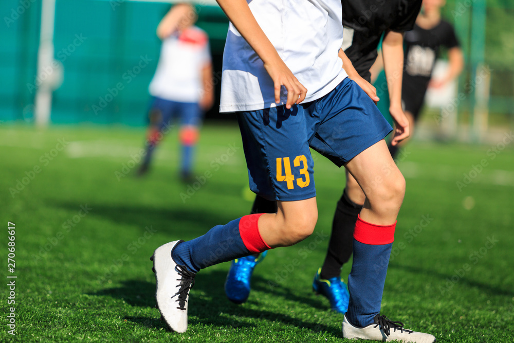 Boys at blue white sportswear run, dribble, attack on football field. Young soccer players with ball on green grass. Training, football, active lifestyle for kids Boys at blue white sportswear run, dribble, attack on football field. Young soccer players with ball on green grass. Training, football, active lifestyle for kids