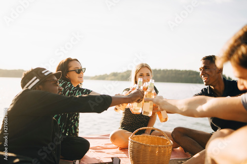 Leende v‰nner skÂlar under picknick vid vattnet photo