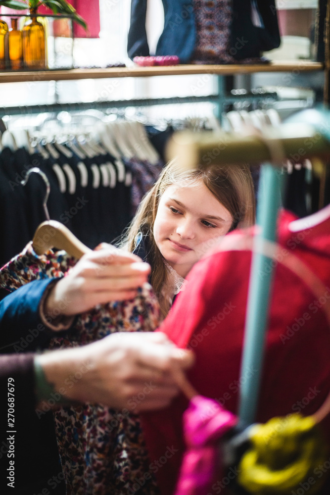 Cute girl looking at dress while shopping in boutique Cute girl looking at dress while shopping in boutique