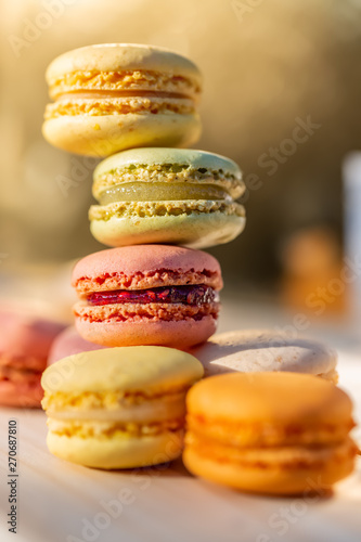 French macarons in the summer evening in the garden. Delicious sweet airy colored French pastries. Shallow depth of field