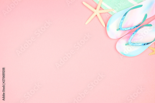 Beach accessories on a pink background. Summer vacation concept. Top view corner border with copy space. Flip flops, sea shells and towel.