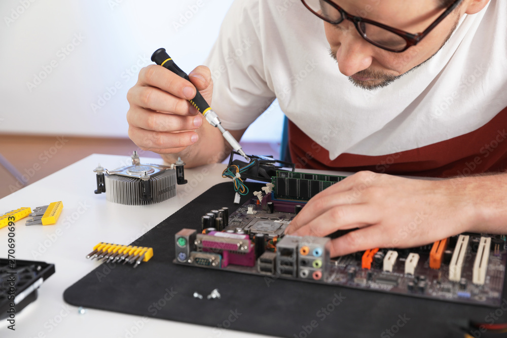 Male technician repairing motherboard at table, closeup Male technician repairing motherboard at table, closeup