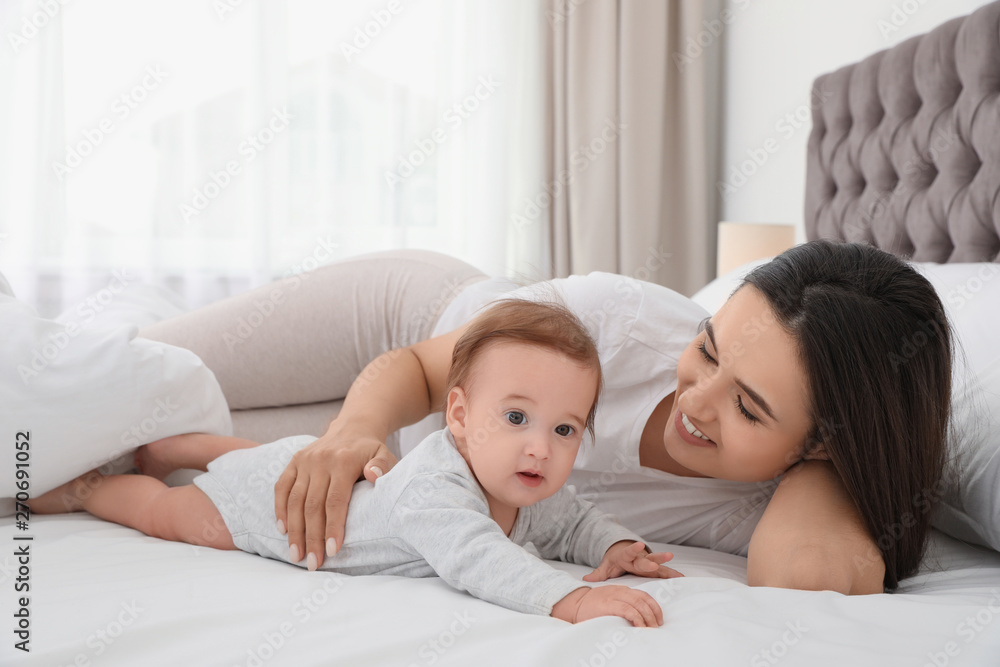 Portrait of mother with her cute baby lying on bed indoors Portrait of mother with her cute baby lying on bed indoors