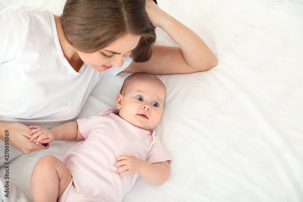 Cute baby with mother lying on bed, above view. Space for text Cute baby with mother lying on bed, above view. Space for text