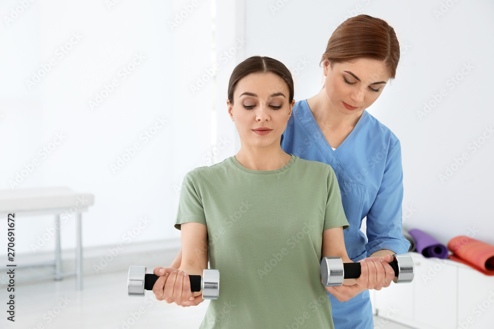 Fototapeta premium Professional physiotherapist working with female patient in rehabilitation center