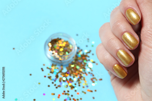 Woman showing manicured hand with golden nail polish over color background, closeup. Space for text