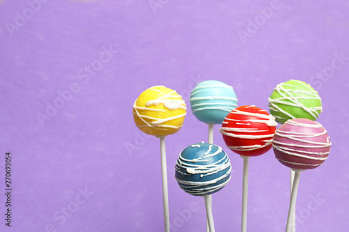 Many bright delicious cake pops on color background. Space for text