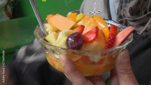 An extreme close up shot of a person holding a fruit saland in a small transparent bowl photo