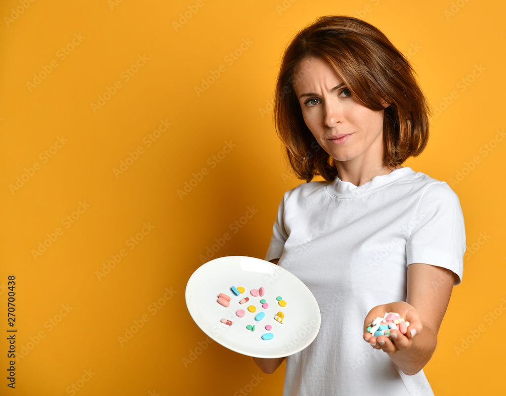 Skeptical doubting woman nutritionis holds in his palm and on white plate diet supplements different color pills weight loss drugs Skeptical doubting woman nutritionis holds in his palm and on white plate diet supplements different color pills weight loss drugs