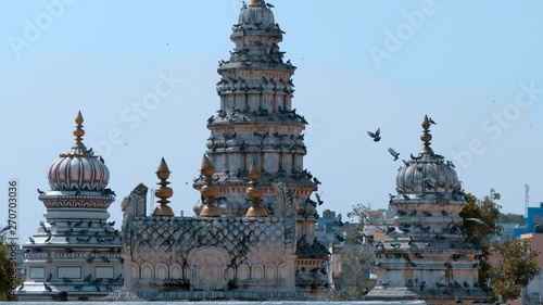 A large flock of pigeons fly over Old Rangji Temple and sit on its dome, in the city of Pushkar, India, one of the sacred pilgrimage sites in Hinduism photo