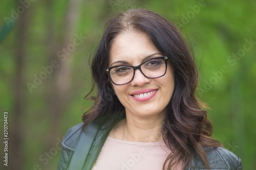 Beautiful, powerful middle-age brunette woman with glasses smiling.