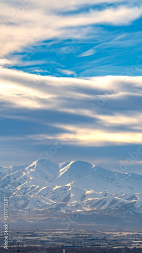 Vertical frame Striking sunlit mountain coated with snow under a vivid blue sky with clouds