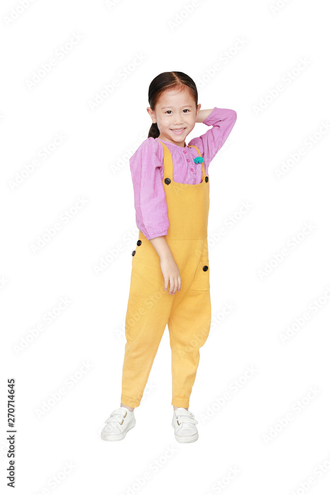 Smiling little Asian kid girl in pink-yellow dungarees poses touched hair keep back isolated on white background. Full length of kid and fashion concept. Smiling little Asian kid girl in pink-yellow dungarees poses touched hair keep back isolated on white background. Full length of kid and fashion concept.