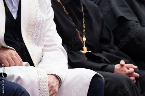 A Muslim mullah in white clothes and a Christian priest in a black cassock are sitting next to each other. The concept of religious cooperation, understanding, tolerance and friendship. photo