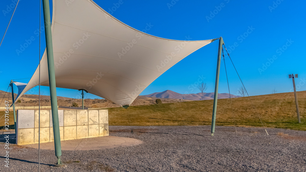 Panorama frame Concrete rectangular structure under a white canopy viewed on a sunny day