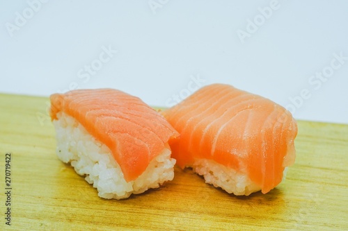 Raw Salmon Nigiri Sushi served on a wooden board against white background, a traditional japanese delicacies