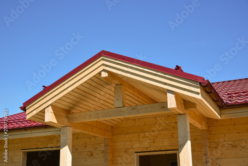 One-storey timber house with a red roof on blue sky. The construction of ecological wood homes. Mortgage, loan, dream house. Ecological material. Country private house.